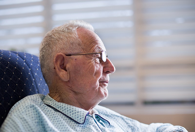 An elderly man sitting on a chair and smiling, representing compassionate hospice care in Allen, TX.